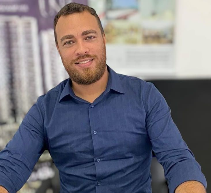 Samuel Laupp, corretor de imóveis em Praia Grande, de camisa azul no escritório